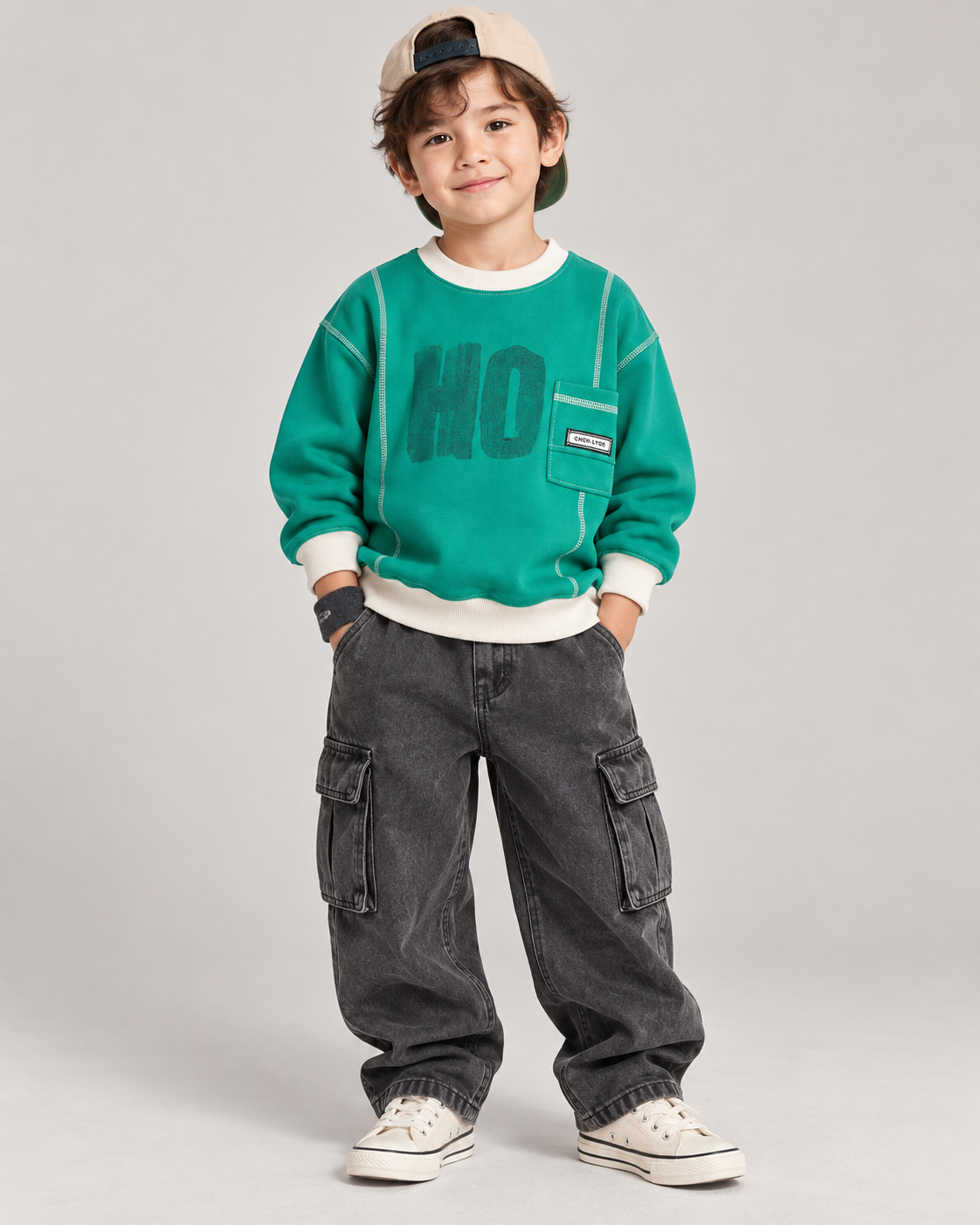 Boy wearing the emerald green contrast-stitch fleece sweatshirt with baggy charcoal cargo pants