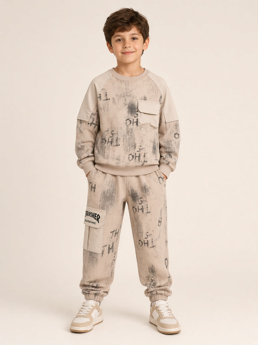 Boy wearing beige distressed graffiti print sweatshirt and matching joggers with THRASHER cargo pocket