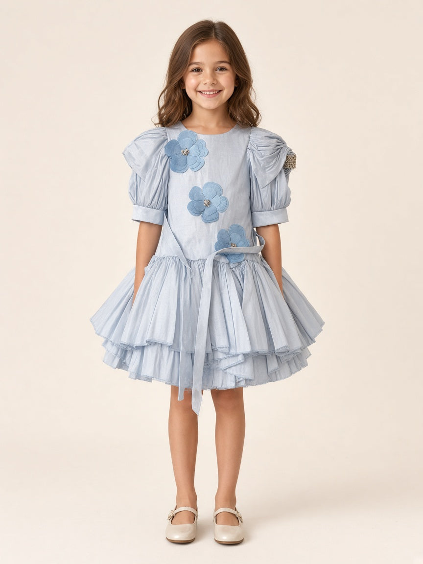 Girl wearing icy blue floral appliqué party frock with puff sleeves and rhinestone sleeve band
