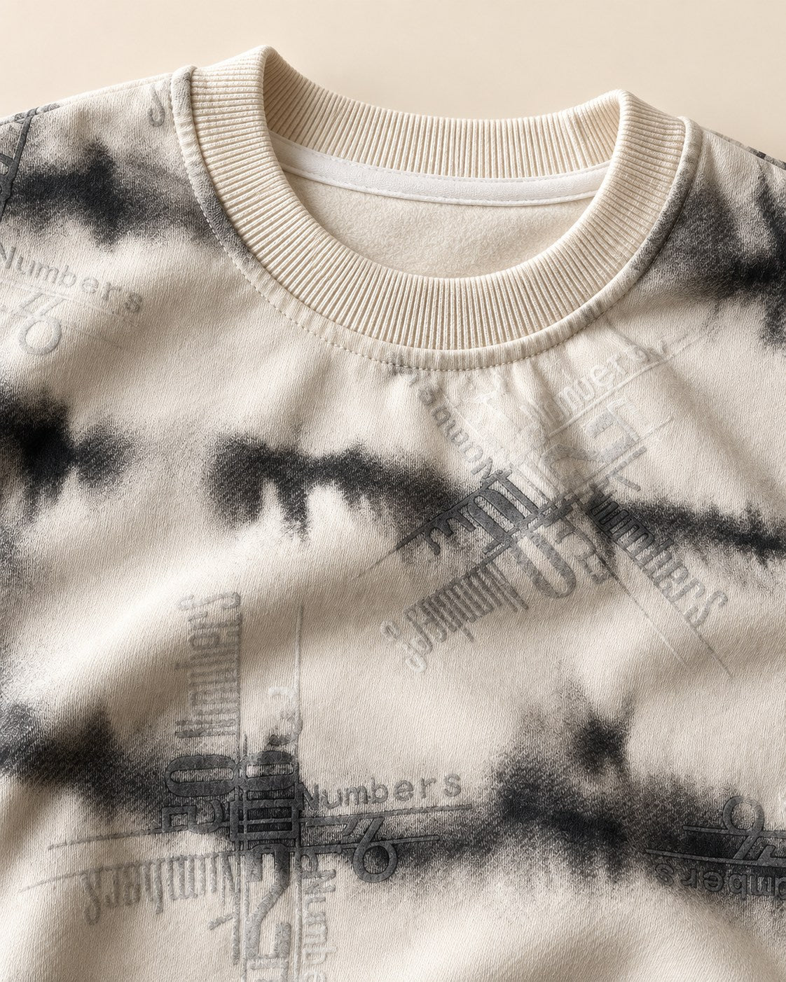 Close detail of cream tie dye sweatshirt collar and tonal graphics